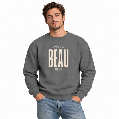 A man wearing a dark gray crewneck sweatshirt with 'D'ACCORD BEAU' printed in beige on the chest, paired with blue jeans, against a plain white background.