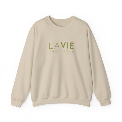 An beige crewneck sweatshirt with “LA VIE CHAOTIQUE” printed in olive green and “BY CHTQ DESIGN” beneath the graphic, displayed against a clean white background.