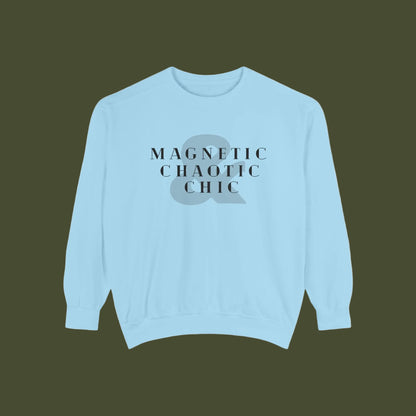 A light blue crewneck sweatshirt with a graphic on the chest featuring the text 'MAGNETIC CHAOTIC CHIC' in black serif font over a gray ampersand symbol.