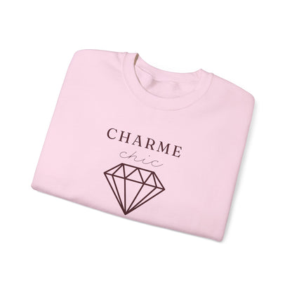 A folded light pink crewneck sweatshirt featuring a burgundy graphic print that reads 'CHARME chic' above a diamond outline, set against a plain white background.