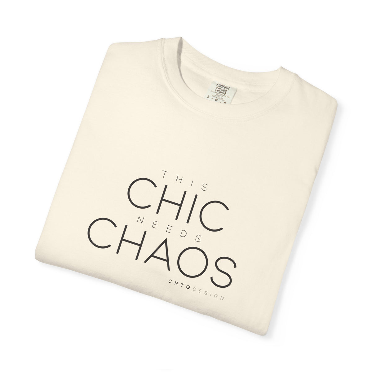 A folded cream-colored t-shirt with black text reading 'THIS CHIC NEEDS CHAOS' and 'CHTCODESIGN' printed below, displayed on a clean white background.