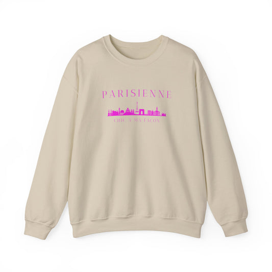 A beige crewneck sweatshirt with a bright pink “PARISIENNE” graphic, Paris skyline design, and “CHIC À MA FAÇON” text on the chest, displayed against a clean white background.