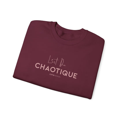 Folded maroon L’ART DU CHAOTIQUE crewneck sweatshirt from back, with minimalist front rose gold typography in front, displayed against a clean white background.