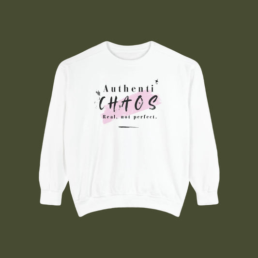 A white crewneck sweatshirt with a graphic print on the chest that reads 'Authenti CHAOS Real, not perfect.' in black text over a light pink paint stroke, displayed on a clean white background.