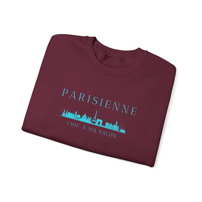 A folded maroon crewneck sweatshirt with a bright turquoise “PARISIENNE” graphic, Paris skyline design, and “CHIC À MA FAÇON” text on the chest, displayed against a clean white background.