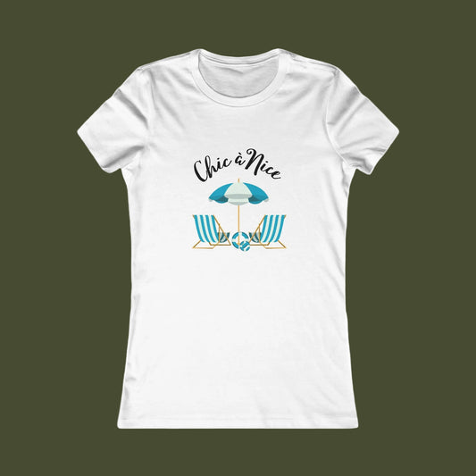 A white short-sleeve crewneck t-shirt with a graphic on the front showing a beach umbrella and two striped beach chairs under the text 'Chic a Nice'.