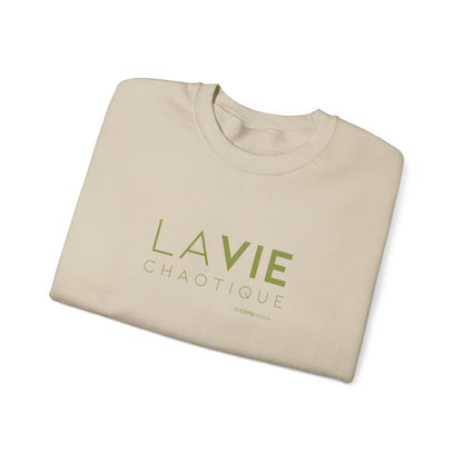 Folded beige crewneck sweatshirt with “LA VIE CHAOTIQUE” printed in olive green and “BY CHTQ DESIGN” beneath the graphic, displayed against a clean white background.