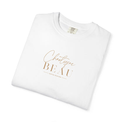 Folded white Chaotique Beau CHTQ Design graphic T-shirt with a gold-toned front print, shown against a white background.