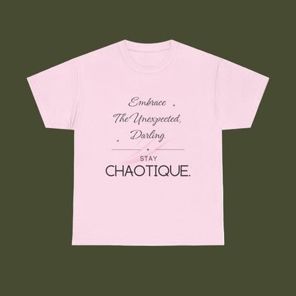 A light pink short-sleeve crewneck t-shirt with a typographic graphic on the front. The text reads 'Embrace The Unexpected, Darling' in a cursive font, followed by a horizontal line, 'STAY CHAOTIQUE.