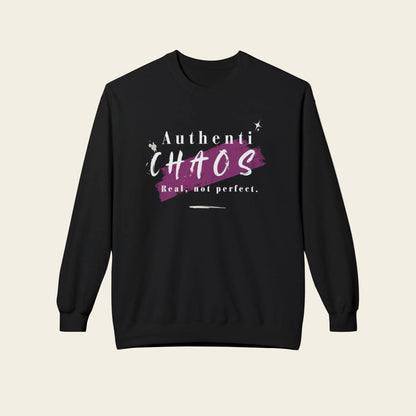A black crewneck sweatshirt with a graphic on the chest that reads 'Authenti CHAOS Real, not perfect.' in white and purple, displayed against a light beige background.