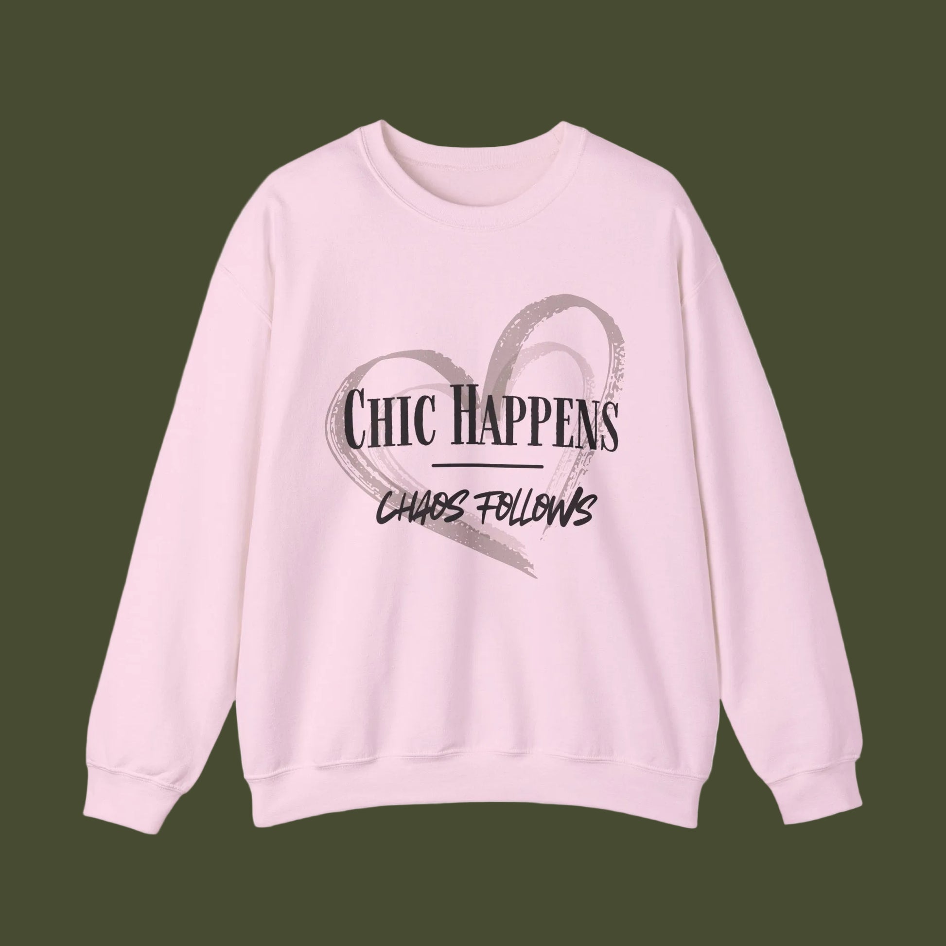 A light pink crewneck sweatshirt featuring a graphic print on the front with a gray brushstroke heart and the text 'CHIC HAPPENS' and 'CHAOS FOLLOWS' in black.