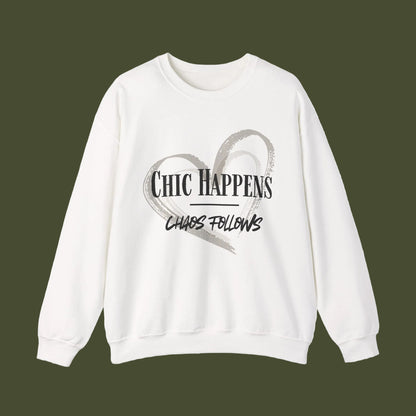 An off-white crewneck sweatshirt featuring a graphic print on the front with a gray brushstroke heart and the text 'CHIC HAPPENS CHAOS FOLLOWS' in black and gray.