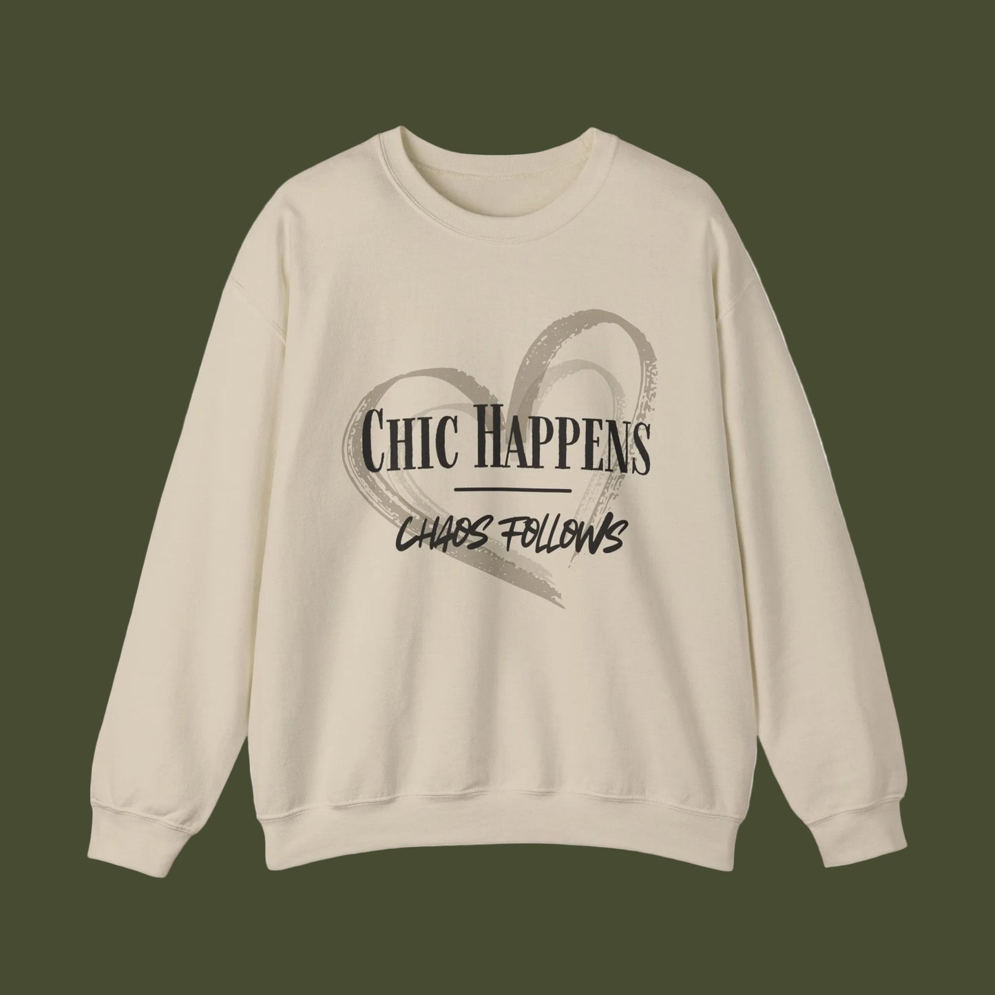 A beige crewneck sweatshirt with a black graphic print on the front featuring a heart outline and the text 'CHIC HAPPENS' and 'CHAOS FOLLOWS'.