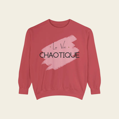 A dusty rose crewneck sweatshirt featuring a graphic print on the front with a pink brushstroke background and the text 'La Vie CHAOTIQUE' in black.