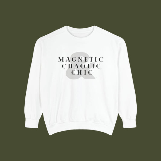 A white crewneck sweatshirt with a graphic print on the chest reading 'MAGNETIC CHAOTIC CHIC' in black serif text over a large gray ampersand symbol.