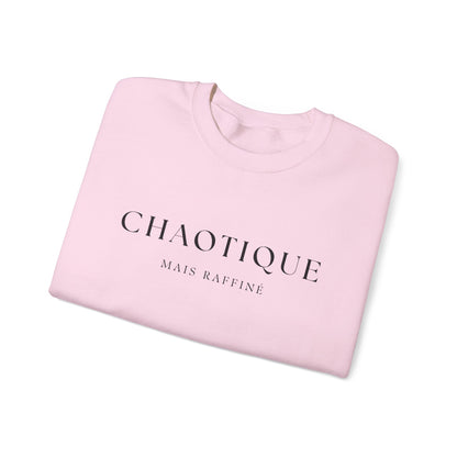 Folded pink sweatshirt with 'Chaotique Mais Raffine' text on a white background