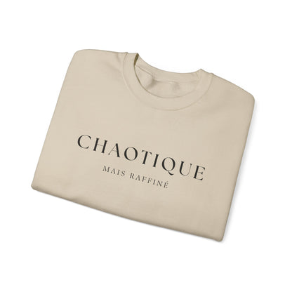 Folded beige sweatshirt with 'Chaotique Mais Raffine' text on a white background