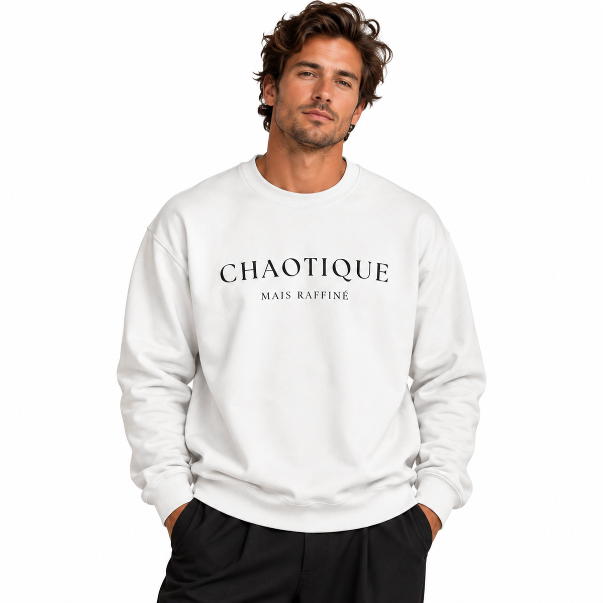 A man wearing a white crewneck sweatshirt with 'CHAOTIQUE MAIS RAFFINÉ' printed in black across the chest, paired with black pants, against a plain white background.