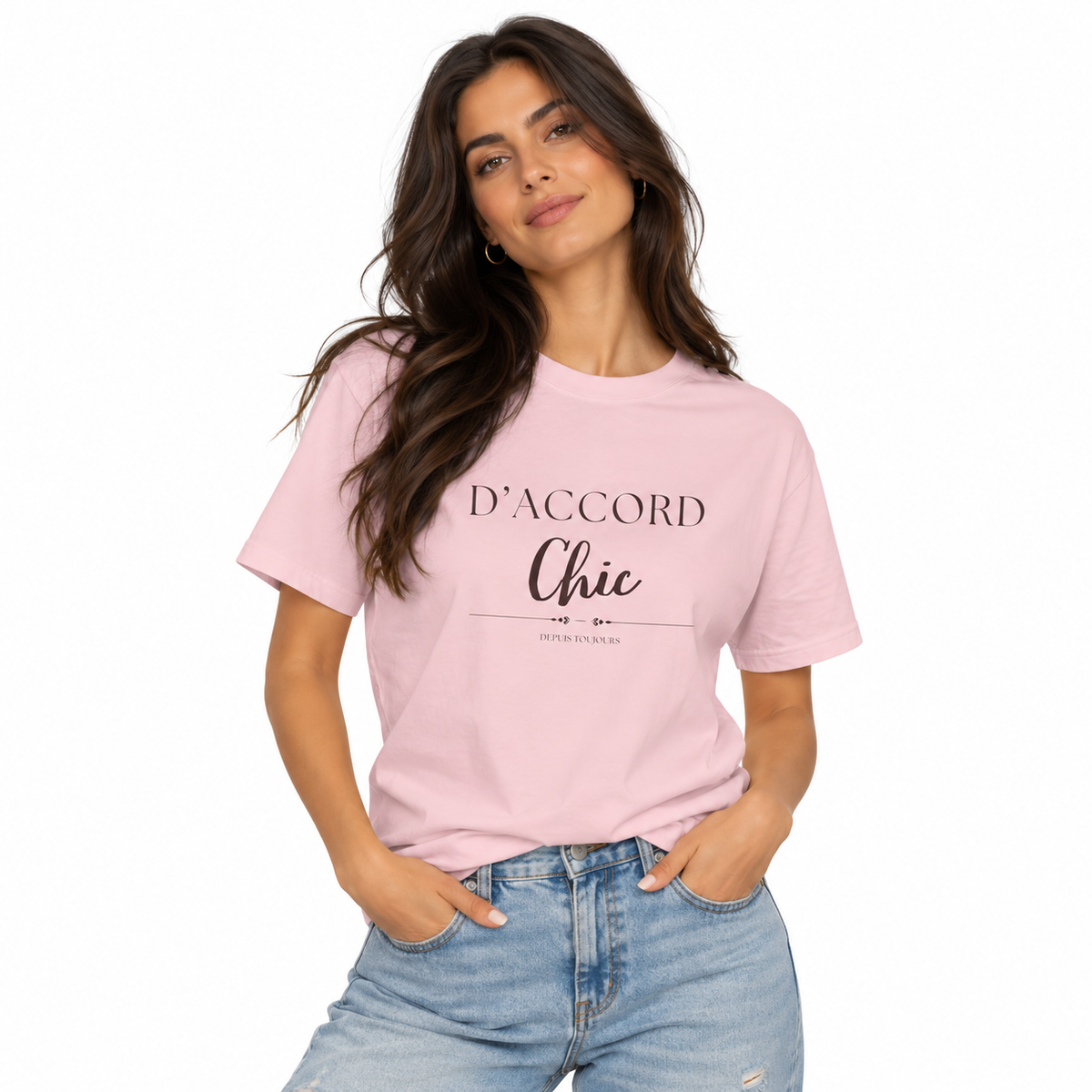 A woman modeling a light pink crewneck t-shirt with black printed text reading 'D'ACCORD Chic' on the front, paired with light-wash blue jeans against a plain white background.