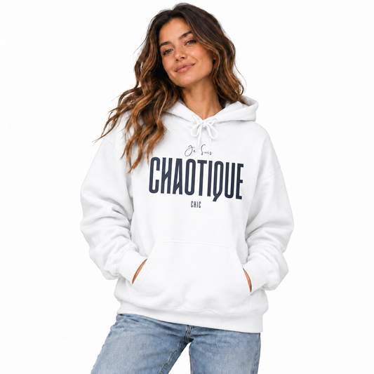 Woman wearing a white Je Suis CHAOTIQUE CHIC graphic hoodie with dark navy lettering, kangaroo pocket and light blue jeans in a white studio.