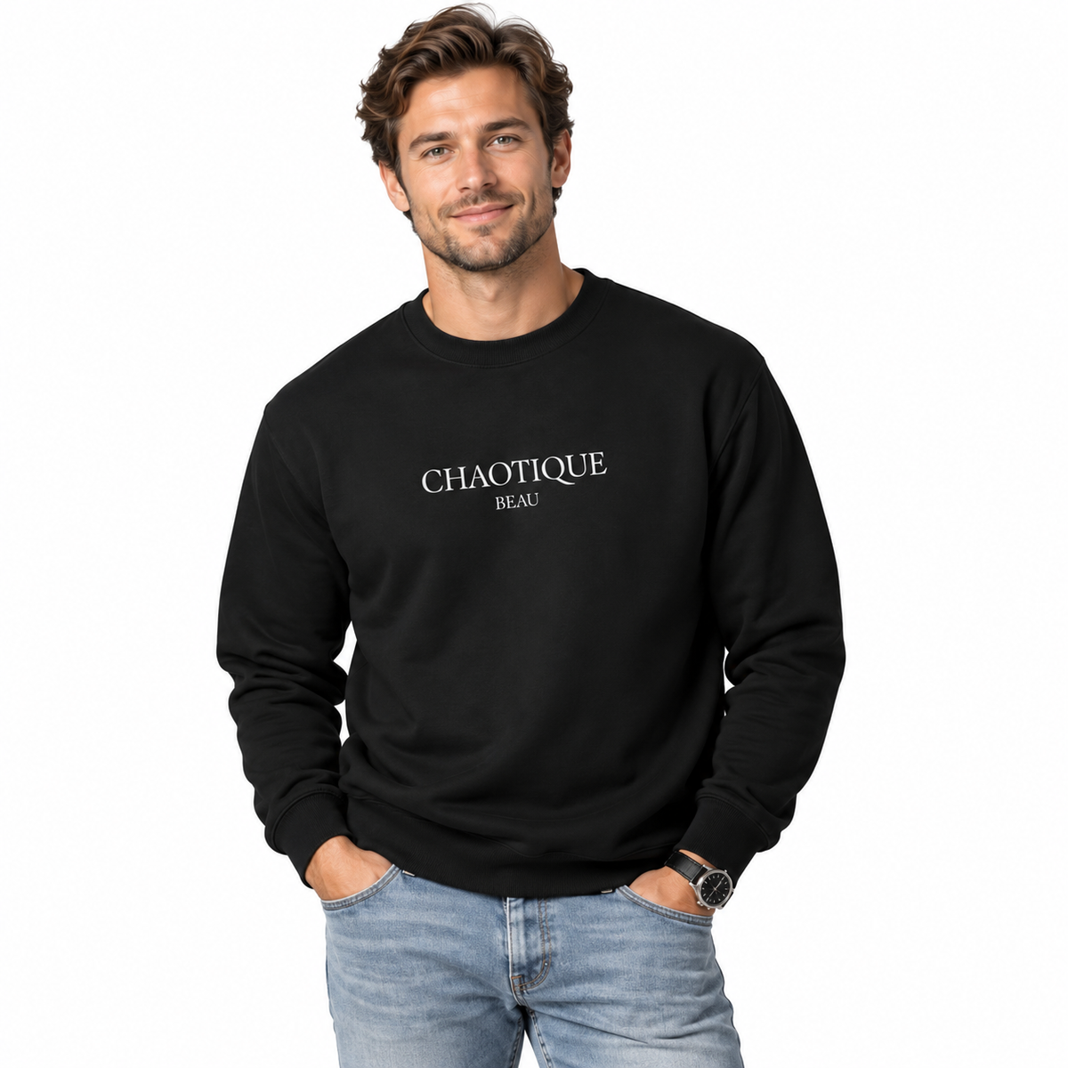 A man wearing a black crewneck sweatshirt with 'CHAOTIQUE BEAU' printed in white text on the chest, paired with light blue jeans, against a plain white background.