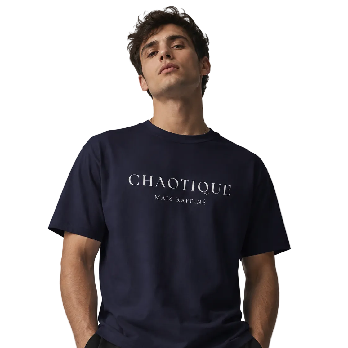 Man wearing a navy blue crewneck T-shirt with white “CHAOTIQUE MAIS RAFFINÉ” slogan print, styled with black pants against a neutral gray studio background.