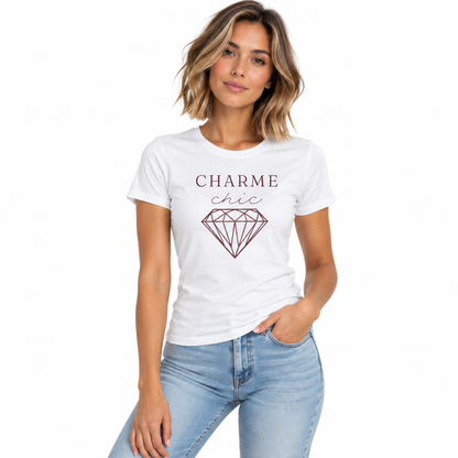 A woman modeling a white short-sleeve t-shirt with a graphic that reads 'CHARME chic' above a diamond illustration in a dusty rose color, paired with light blue jeans against a plain white background.