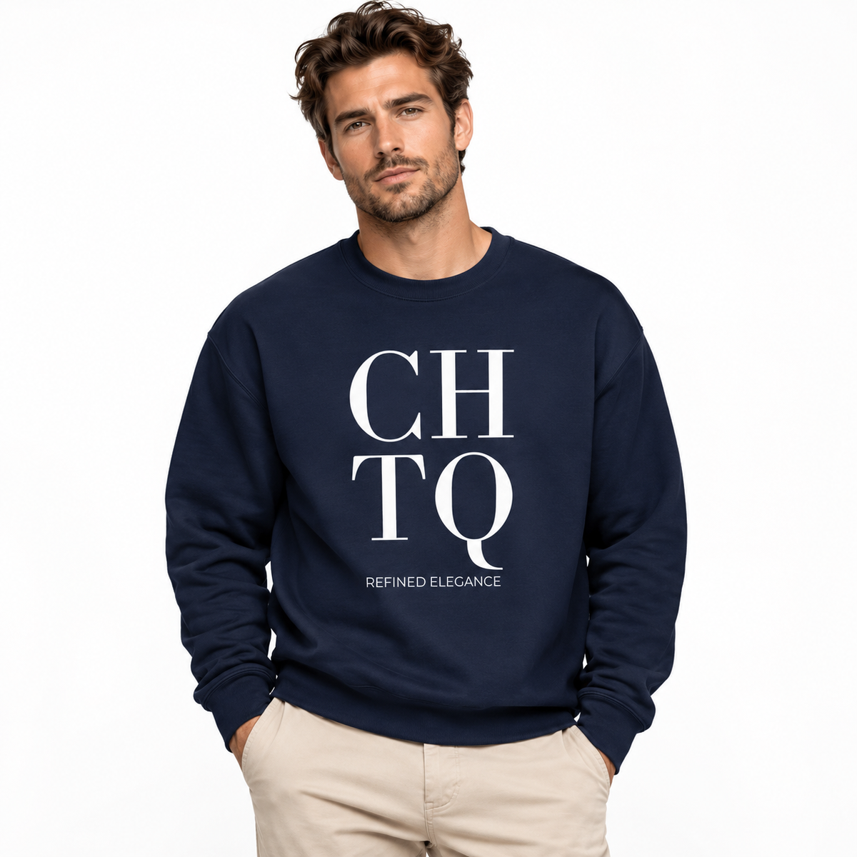 A man wearing a navy blue crewneck sweatshirt with a bold white graphic print reading 'CHTQ' and 'REFINED ELEGANCE' underneath, paired with beige pants, against a plain white background.