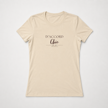 Beige short-sleeve crewneck T-shirt featuring the “D’Accord Chic” graphic in black and brown lettering on the front, displayed against a light gray background.