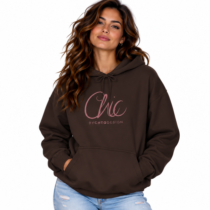A woman wearing a dark brown pullover hoodie with a pink 'Chic' and 'BY CHTQ DESIGN' graphic on the chest, paired with light blue jeans, set against a plain white background.
