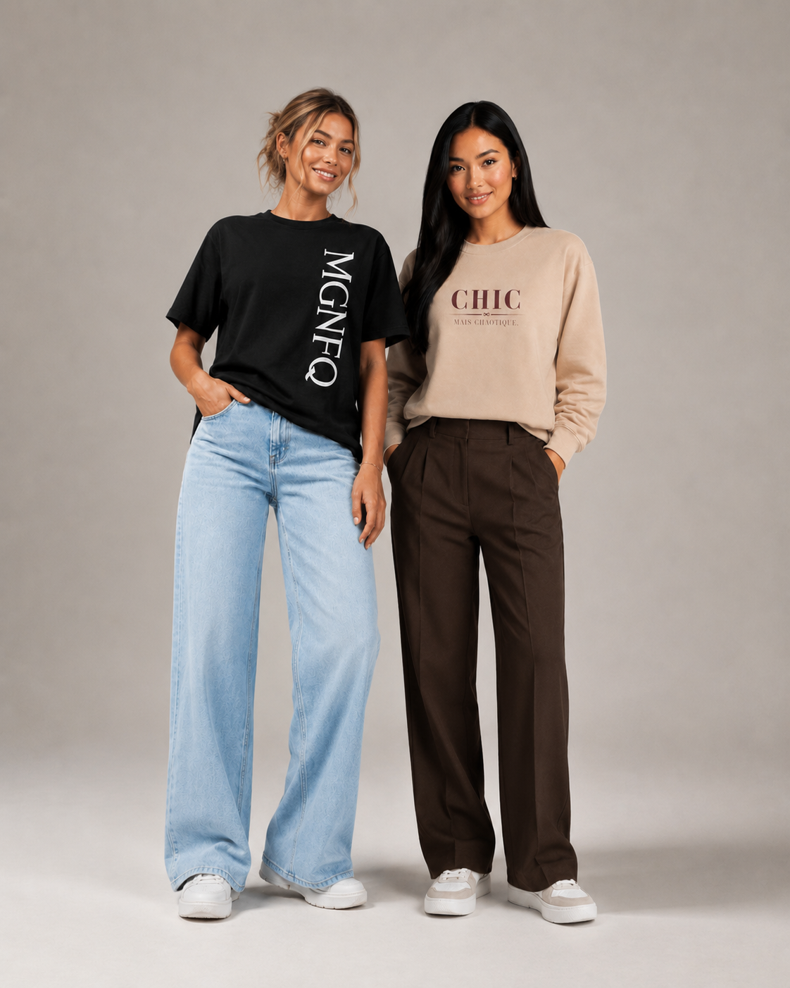Two women modeling apparel in a studio setting. The woman on the left wears a black graphic T-shirt with vertical white text and light blue wide-leg jeans.