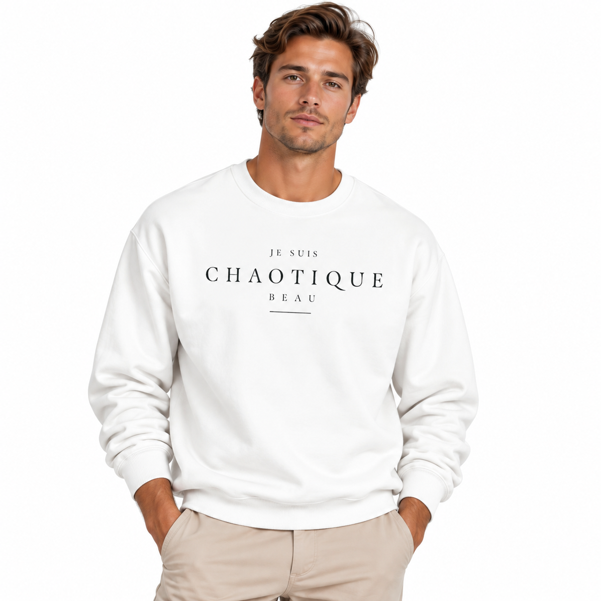 A man wearing a white crewneck sweatshirt with black text reading 'JE SUIS CHAOTIQUE BEAU' on the chest, paired with beige pants, against a plain white background.