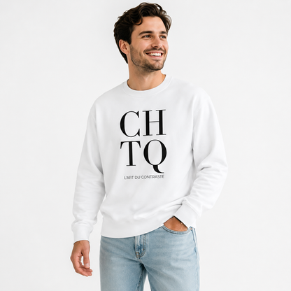 A smiling man wearing a white CHTQ graphic crewneck sweatshirt with black “CHTQ” and “L’ART DU CONTRASTE” print, paired with light blue jeans on a clean white studio background.