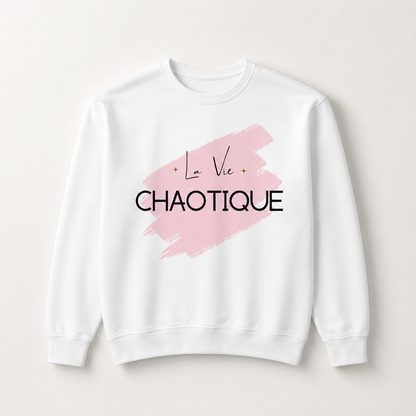 White crewneck sweatshirt featuring the “La Vie Chaotique” graphic in black over a soft pink brushstroke on the front, displayed against a light beige background.