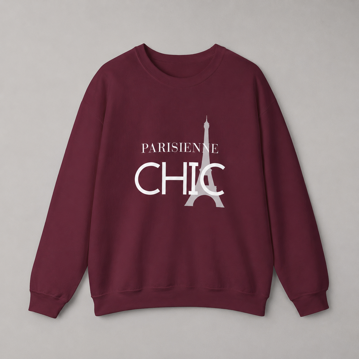 Maroon crewneck sweatshirt featuring a white “PARISIENNE CHIC” graphic with a stylized Eiffel Tower, displayed against a neutral gray studio background.