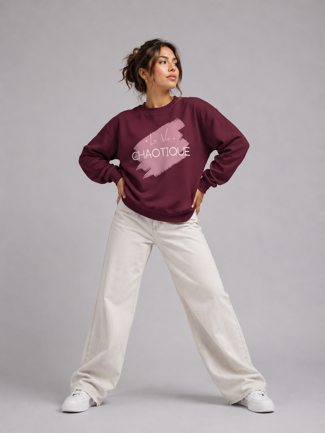 Woman wearing La Vie Chaotique graphic sweatshirt with white trrendy jeans and white sneakers