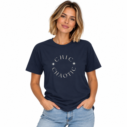 A woman wearing a navy blue crewneck t-shirt with a white graphic that reads 'CHIC CHAOTIC' in a circle with small star accents, paired with light blue jeans, against a plain white background.