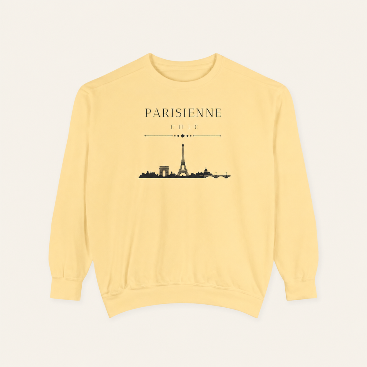 Butter color crewneck sweatshirt featuring the “Parisienne Chic” graphic with a black Paris skyline on the front, displayed against a light beige background.