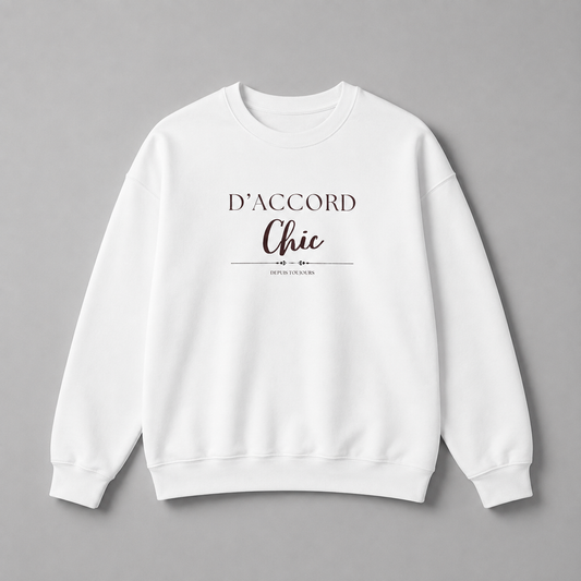 White D’Accord Chic crewneck sweatshirt with dark brown chest typography, displayed flat against a neutral grey studio background.